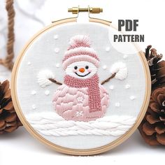 a snowman with a pink hat and scarf is shown in the hoop