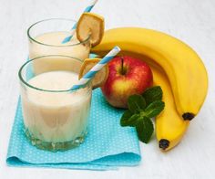 two glasses of milk, an apple and banana on a blue napkin