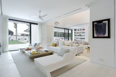 a living room filled with white furniture and large windows