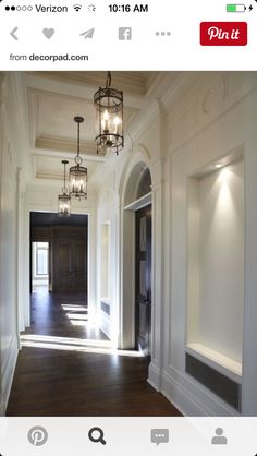 an empty hallway with chandelier and wooden floors