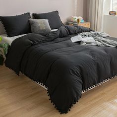 a bed with black comforter and pillows on it