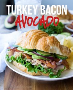 a turkey bacon avocado croissant sandwich on a white plate