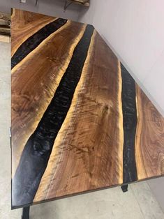 a wooden table with black and gold stripes on it's surface in a room