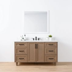 a bathroom vanity with two sinks and a mirror on the wall above it, in front of a white wall