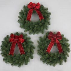 three christmas wreaths with red bows on them