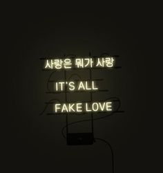 a neon sign that says it's all fake love in korean writing on a black background