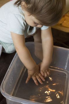 a young child playing with water in a plastic container