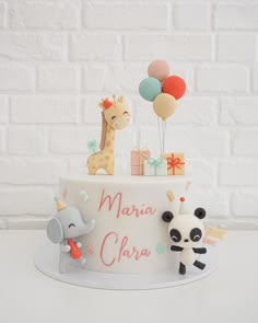 a birthday cake with an elephant, giraffe and balloon on top that says maria clara