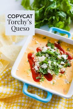 a square white bowl filled with soup next to tortilla chips and cilantro