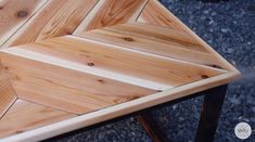 a close up of a wooden table with metal legs on graveled ground next to rocks