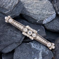 This circa 1930s bar brooch is quintessentially Art Deco and features a pierced design with engraved details that is bordered with milgrain edging. The brooch is accented with a total of thirty-seven (37) bead and prong set old European cut diamonds. The brooch measures approximately 3.5 inches long by 0.5 inches wide.  It is crafted in platinum and is finished with a 14k white gold pin stem.  The catch is silver-tone. Cartier Art Deco, Bar Brooch, Art Deco Brooch, 1930s Art, Gold Pin, The Catch, 1930s Art Deco, Diamond Bar, European Cut Diamonds