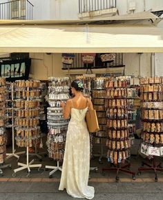 a woman standing in front of a store with lots of items on the display shelves