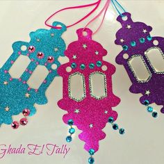 three different colored tags hanging from strings on a white surface with pink, blue and green beads