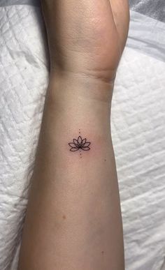 a small lotus tattoo on the wrist is shown in black ink, and has a tiny flower