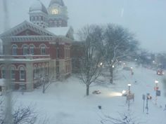 a building with a clock tower in the middle of it on a snow covered street