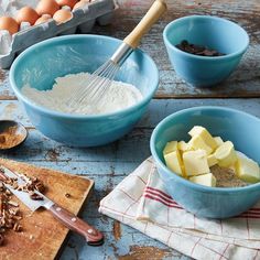 two blue bowls filled with ingredients on top of a wooden table next to an egg carton