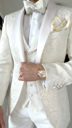 a man in a white tuxedo with a watch on his left hand and gold accents