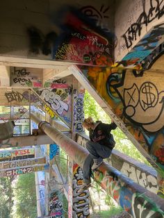 a man climbing up the side of a bridge covered in graffitti and spray paint