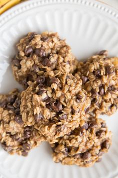 three oatmeal cookies on a white plate with a banana in the background