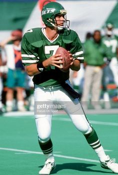 a football player holding a ball in his hands on the field with other players watching