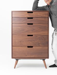 a man leaning on a chest of drawers