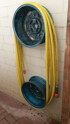 there is a yellow hose attached to the wall next to a blue bucket with two wheels on it