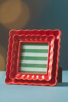 an empty red plate with a green and white striped square in the middle on a blue surface