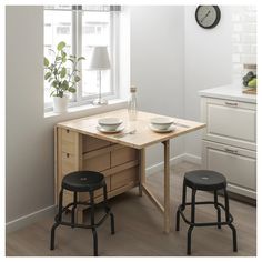 a kitchen table with two stools next to it and a clock on the wall