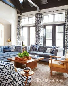 a living room filled with blue couches and chairs in front of large open windows