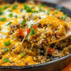 a casserole dish with rice, ground beef and green onions is being scooped from the skillet