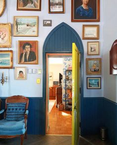 a room with pictures on the wall and a blue chair in front of an open door