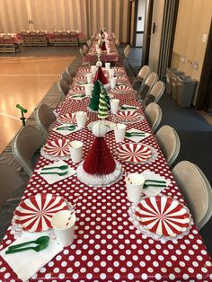 a long table is decorated with red and white polka dot paper plates, candy canes, green napkins, and christmas trees