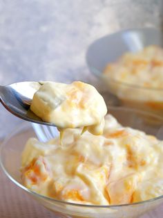 a spoon with some food in it on top of a glass bowl next to another bowl