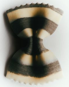 an odd shaped object on a white surface with black and brown stripes in the middle