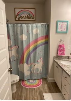 a bathroom with a unicorn shower curtain next to a toilet