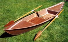 a small wooden boat with oars on the grass