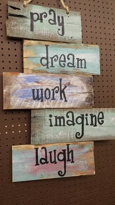 three wooden signs that say pray, dream, work and imagine laugh on the wall