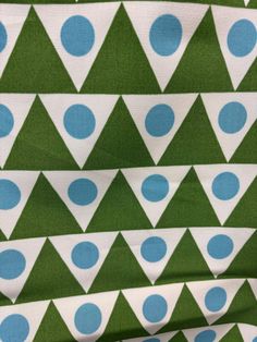 a green and blue fabric with white polka dots on the bottom, and triangle shapes on the top