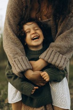 a woman holding a child in her arms and laughing at the same time as they both laugh