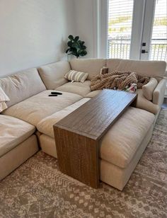 a living room with a large sectional couch and coffee table in it's center