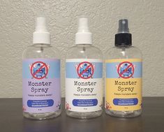 three bottles of monster spray sitting on top of a table