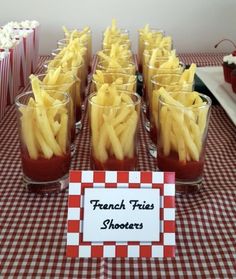 french fries are arranged in glasses on a table with red and white checkered cloth