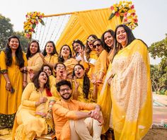 a group of people posing for a photo in front of a yellow drape with flowers on it