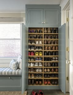 a shoe rack in the corner of a room next to a window and a bench