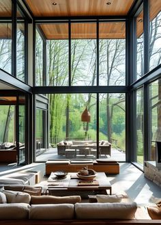 a living room filled with lots of furniture next to large glass windows on top of a wooden ceiling