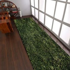 a living room with wood flooring and green rugs on the floor in front of a large window