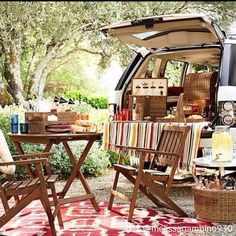 an outdoor picnic area with chairs, table and food in the back of a van