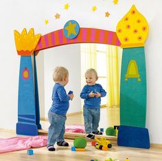 two toddlers playing with toys in front of a mirror on the floor at a children's playroom