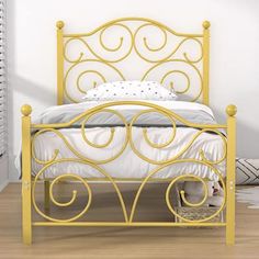 a yellow metal bed with white sheets and pillows