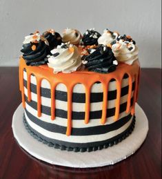 an orange and black cake with white frosting drizzled on the top